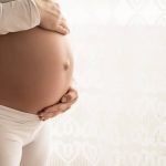 Belly of a pregnant woman on a white background